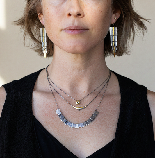 Dangling silver-gray rectangle earrings with gold bars, worn by model