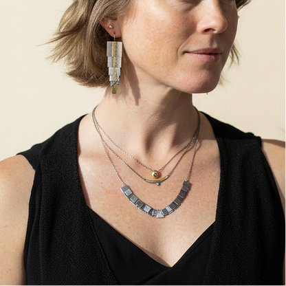 Side view of silver-gray and gold dangling rectangle earrings