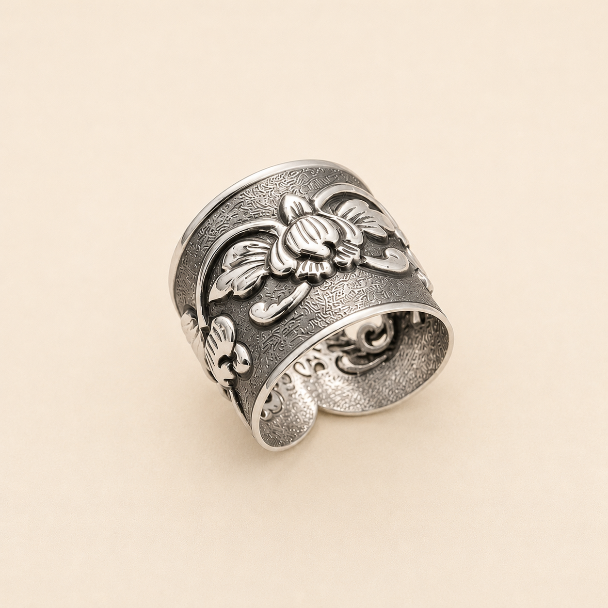 Silver-tone floral engraved ring with raised flower and leaf details on a wide band