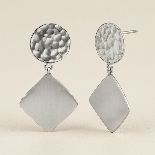 Silver textured drop earrings with round top and diamond dangle, hanging from hooks