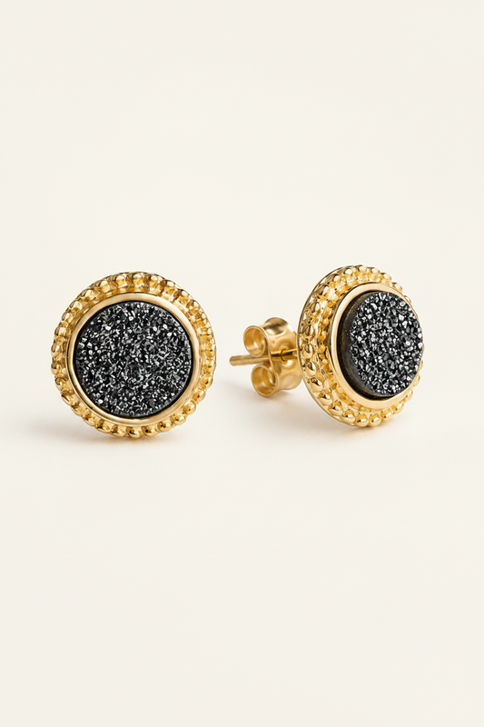 Gold earrings with black druzy stones on a white background
