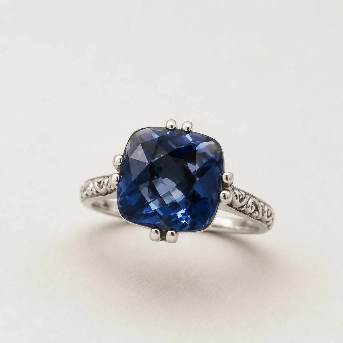 Silver filigree ring with faceted blue cushion gemstone and four prongs