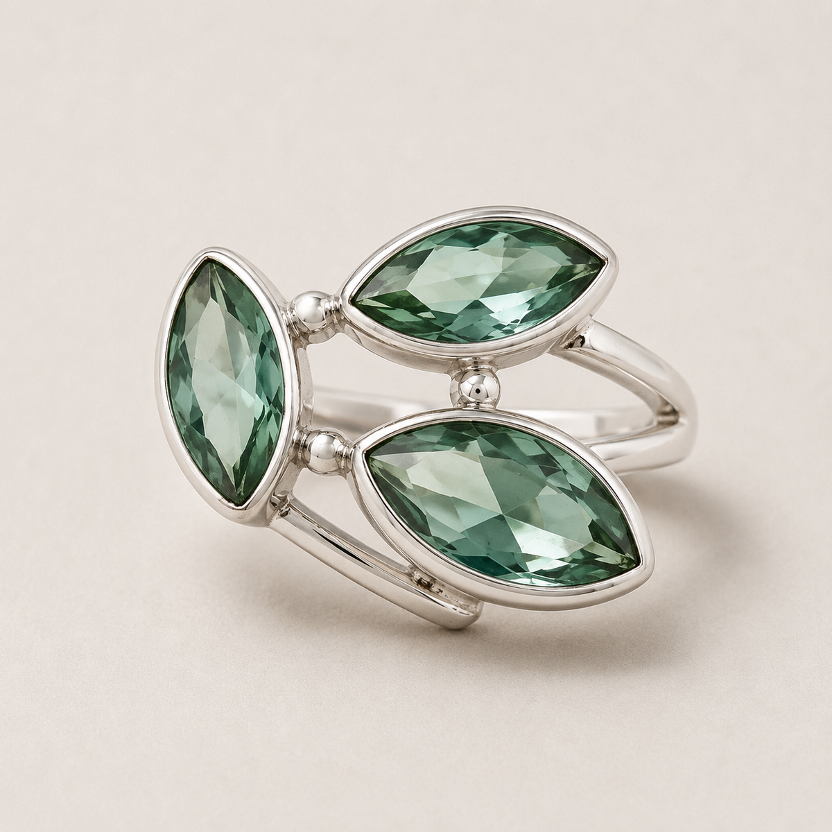 Silver ring with three green teardrop gemstones in petal settings