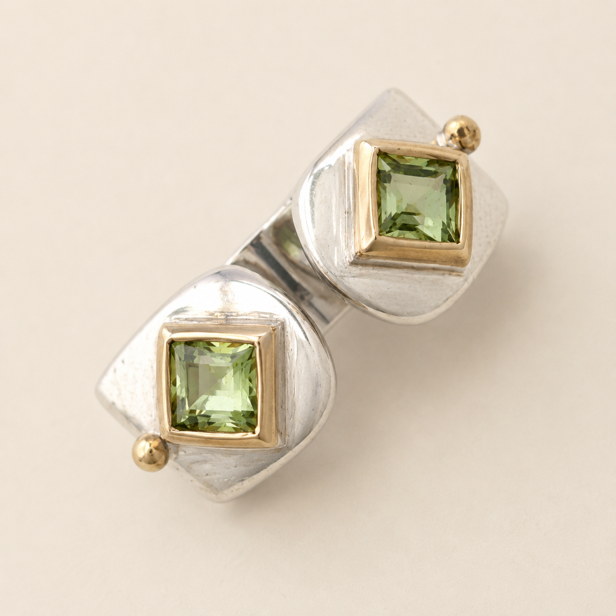 Two-tone peridot ring with two square green stones in silver and gold settings