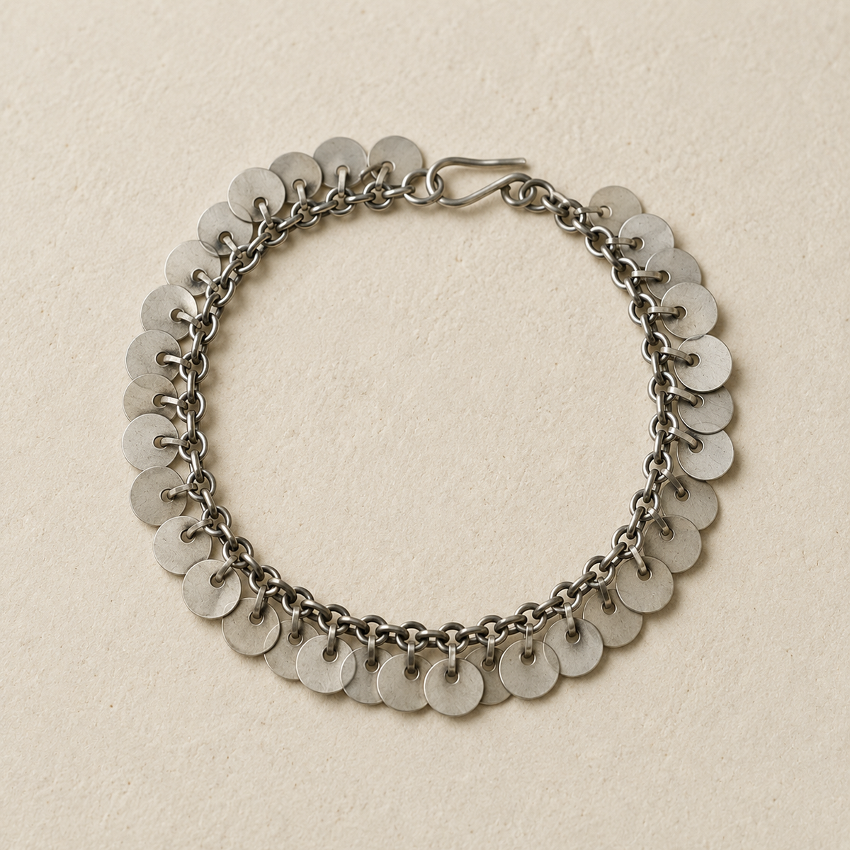 Silver chain bracelet with rows of round disc charms, flat lay view