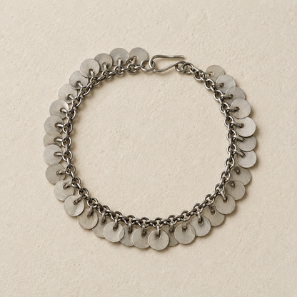 Silver chain bracelet with rows of round disc charms, flat lay view