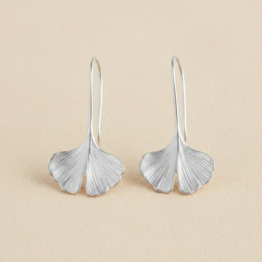 Silver ginkgo leaf drop earrings with curved leaf shapes and narrow hoop hooks.