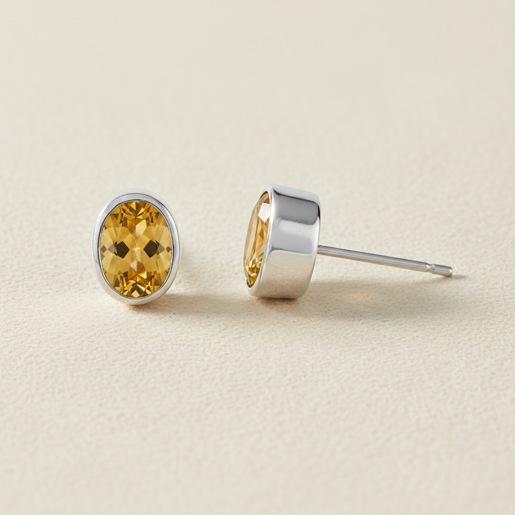Oval yellow gemstone stud earrings with silver bezel and post backing.