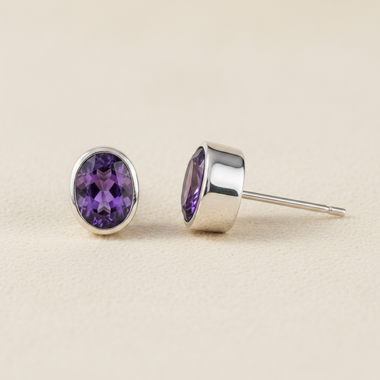 Oval amethyst purple gemstone stud earrings with silver bezel and post backing.
