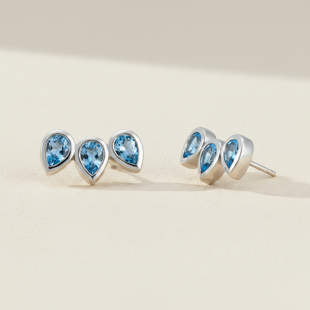Blue topaz pear gemstone stud earrings with three teardrop studs in silver-tone.