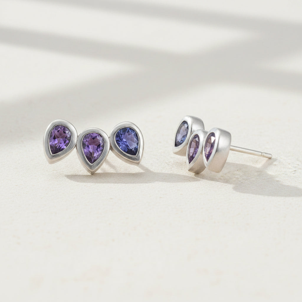 Amethyst pear gemstone stud earrings with three teardrop studs in silver-tone.