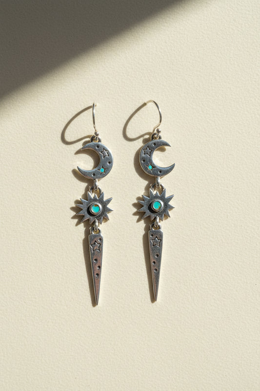 Stardust earrings with dangling crescent moons, blue starburst gems, and long teardrop charms