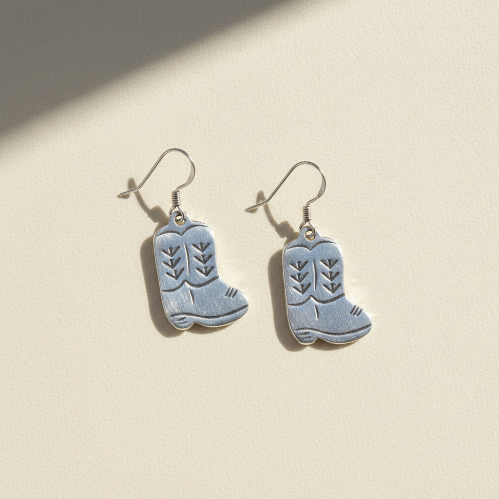 Silver cowboy boot earrings on a white background