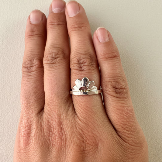 Silver flower crown ring with white petals and gold bead center on slim band