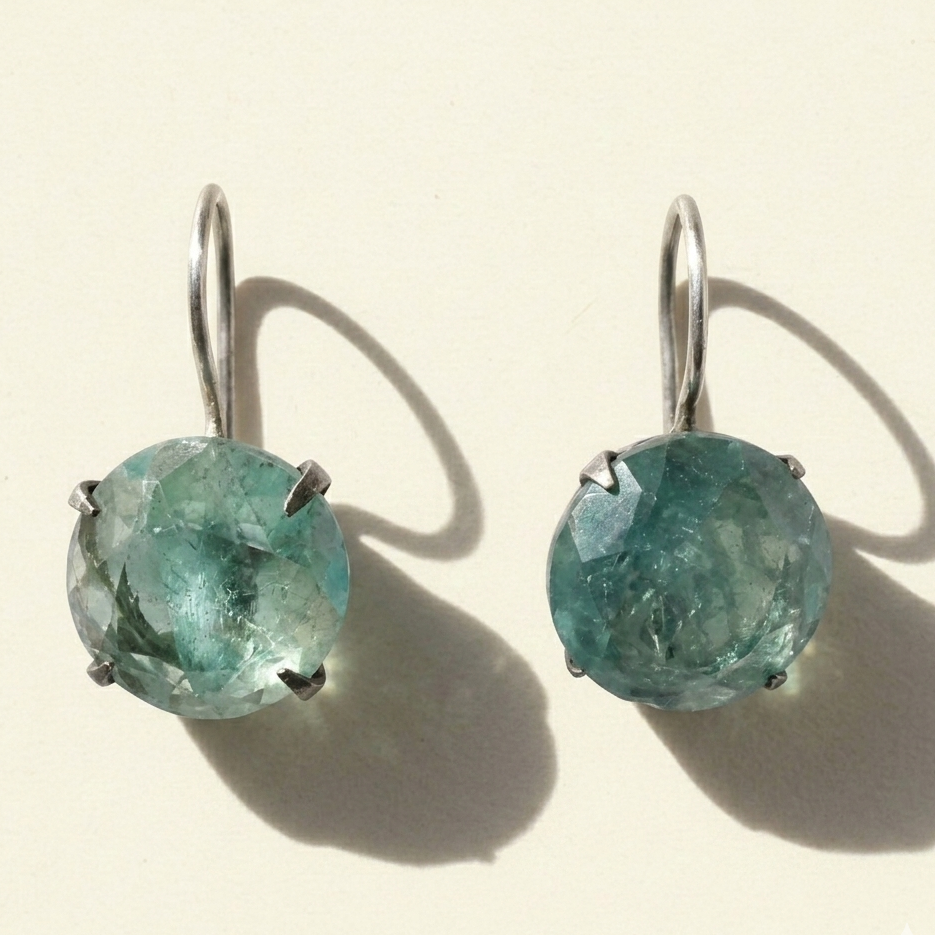 Silver-tone drop earrings with round faceted teal stone in prong setting