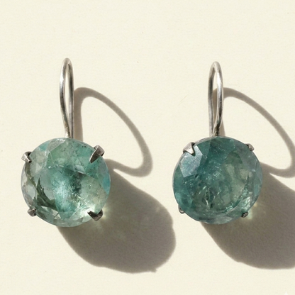 Silver-tone drop earrings with round faceted teal stone in prong setting