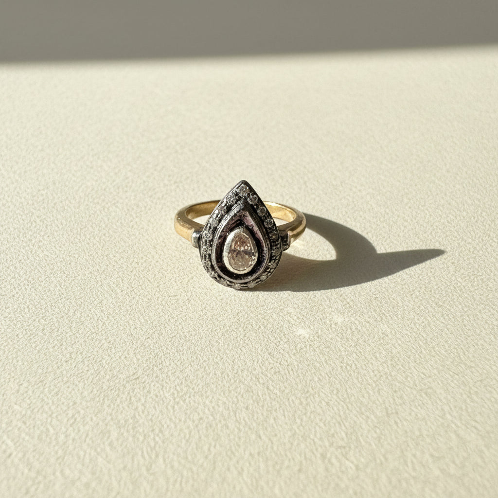 Two-tone teardrop diamond ring with pave halo and round center stone on gold band