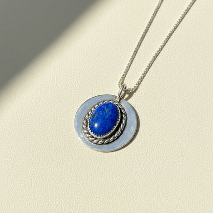 Silver-tone pendant necklace with oval blue lapis-like stone in braided ring