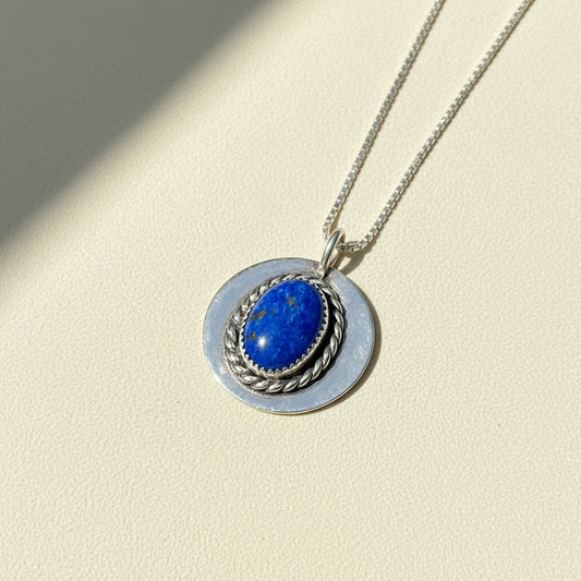 Silver-tone pendant necklace with oval blue lapis-like stone in braided ring