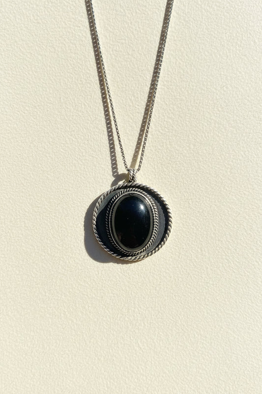Shield pendant necklace with dark oval cabochon and textured outer ring