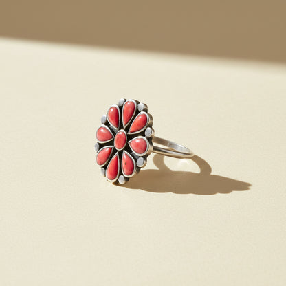 Coral flower ring with silver-tone band and red teardrop stone petals, side view