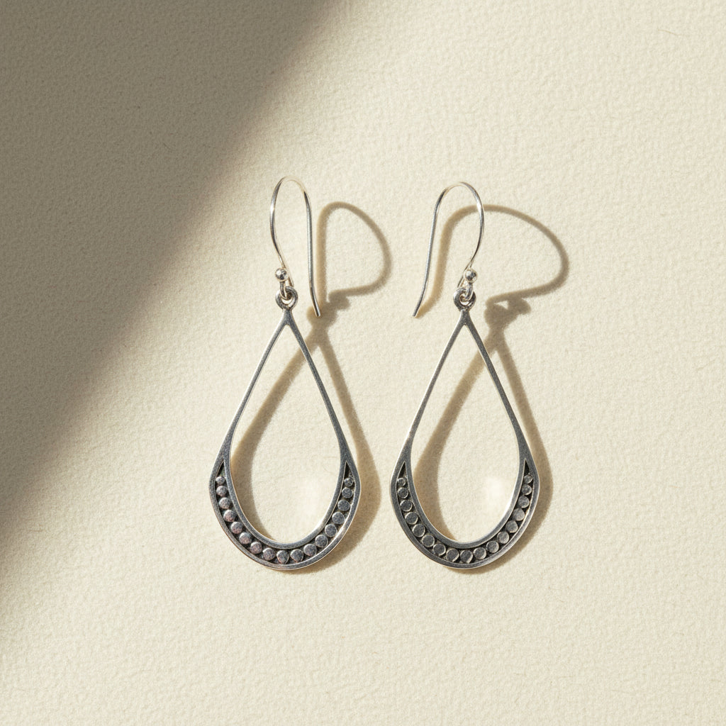 Small silver teardrop beaded earrings with textured border and hanging hook