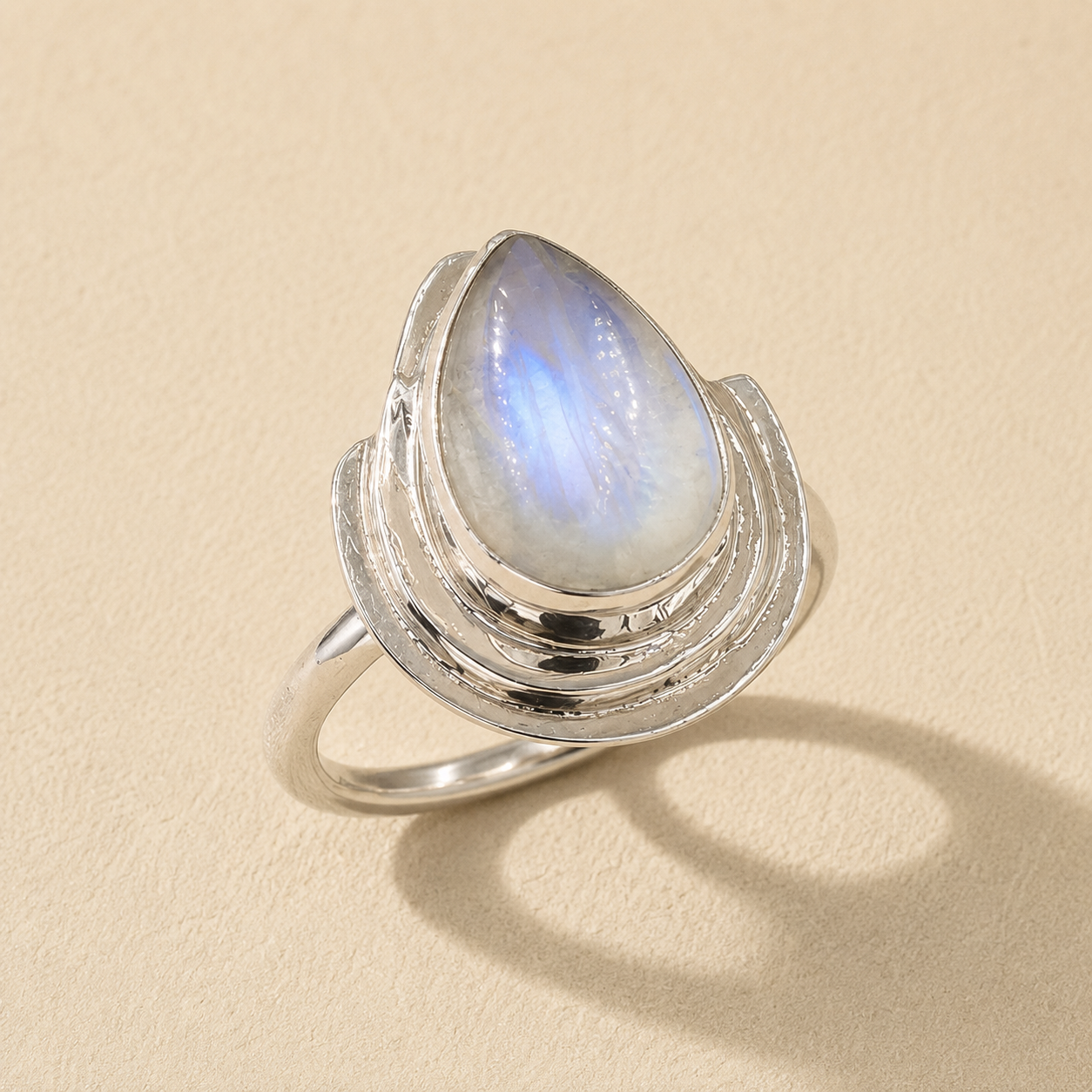 Silver teardrop moonstone ring with round blue iridescent glow on split band