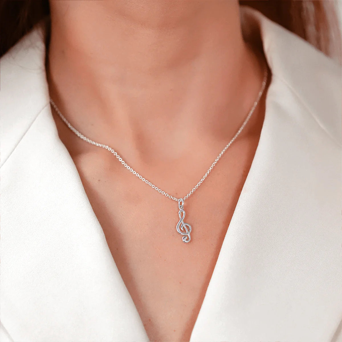 Treble clef pendant necklace on fine silver chain, close to neckline