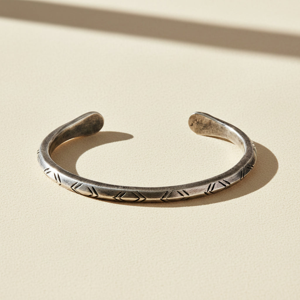 Silver-tone cuff bracelet with engraved zigzag and braided pattern along band