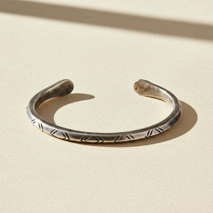 Silver-tone cuff bracelet with engraved zigzag and braided pattern along band