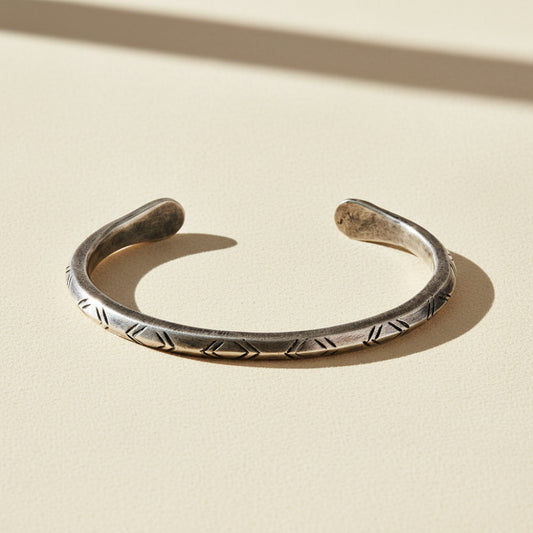 Silver-tone cuff bracelet with engraved zigzag and braided pattern along band