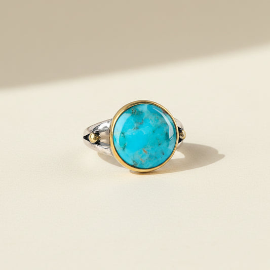 Turquoise oval gemstone ring with gold bezel and silver band, small side stones