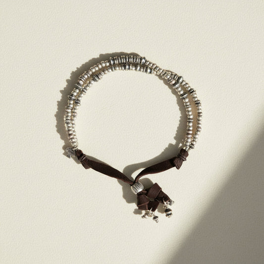 Necklace with silver beads and black ribbon on a white background