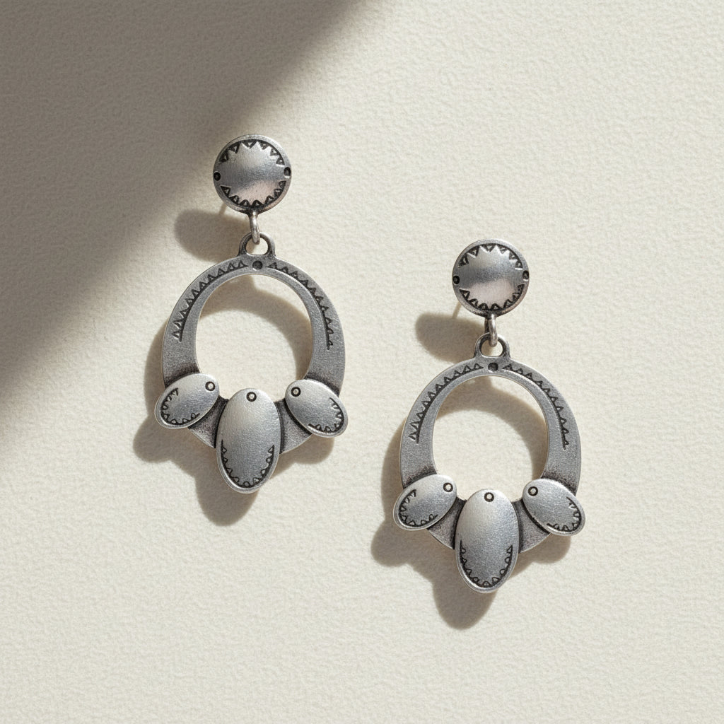 Pair of silver earrings with circular designs on a white background
