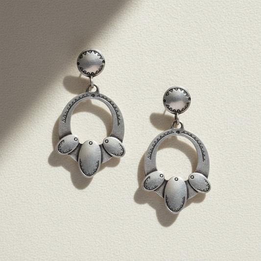 Pair of silver earrings with circular designs on a white background