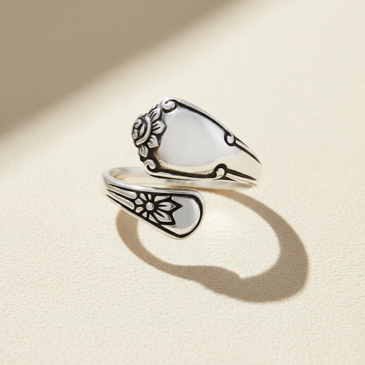 Silver spoon-shaped ring with engraved floral swirls and curved band