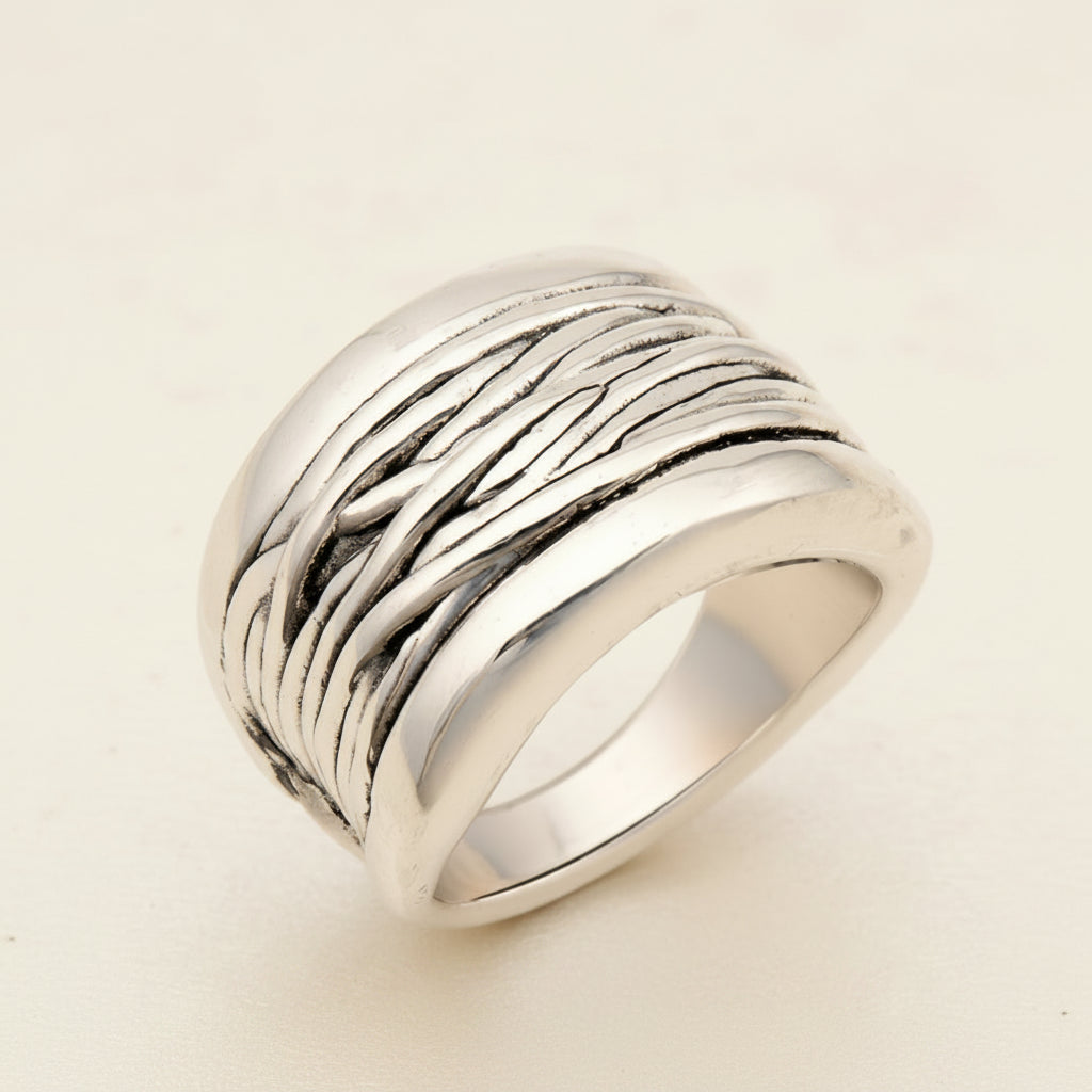 Silver ring with textured design on a white background