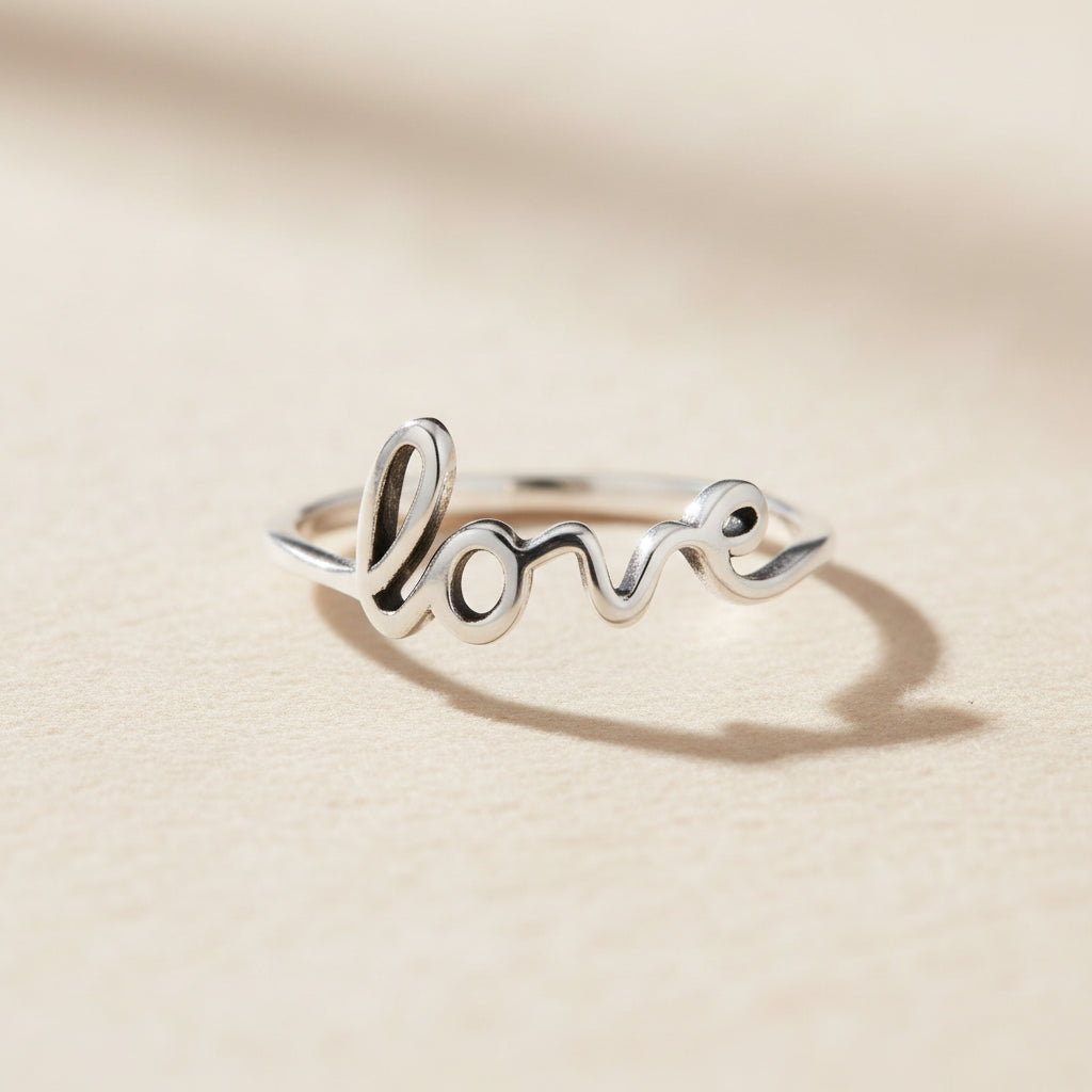 Silver-toned Love script ring with raised cursive lettering and heart dot