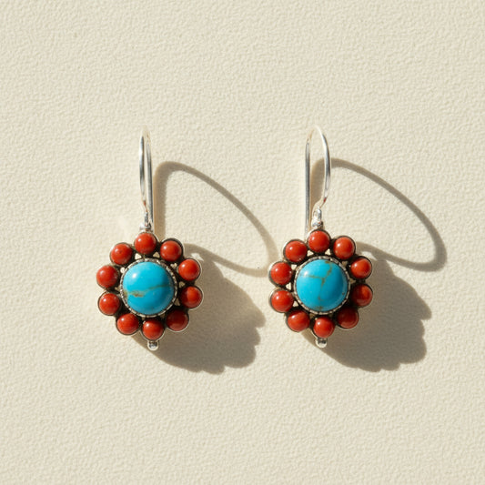 Pair of earrings with blue center and red accents on a white background