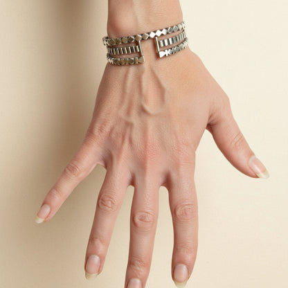 Diamond pattern cuff bracelet on wrist, silver-toned bands with black inlays