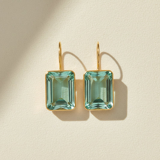 Gold-tone earrings with emerald-cut teal rectangular stones and drop hooks