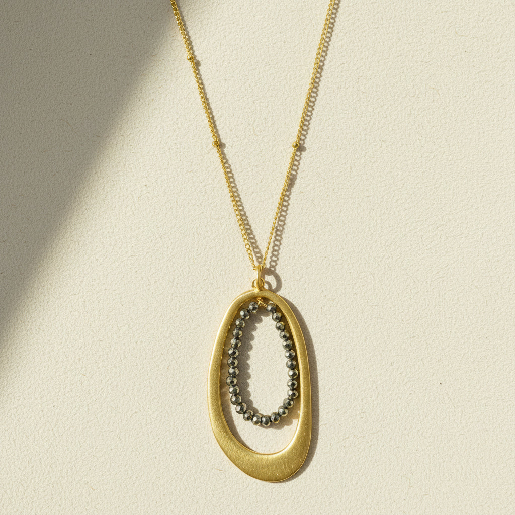 Oval pyrite-bead pendant necklace with gold chain and oval metal frame