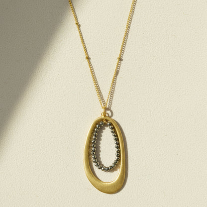 Oval pyrite-bead pendant necklace with gold chain and oval metal frame