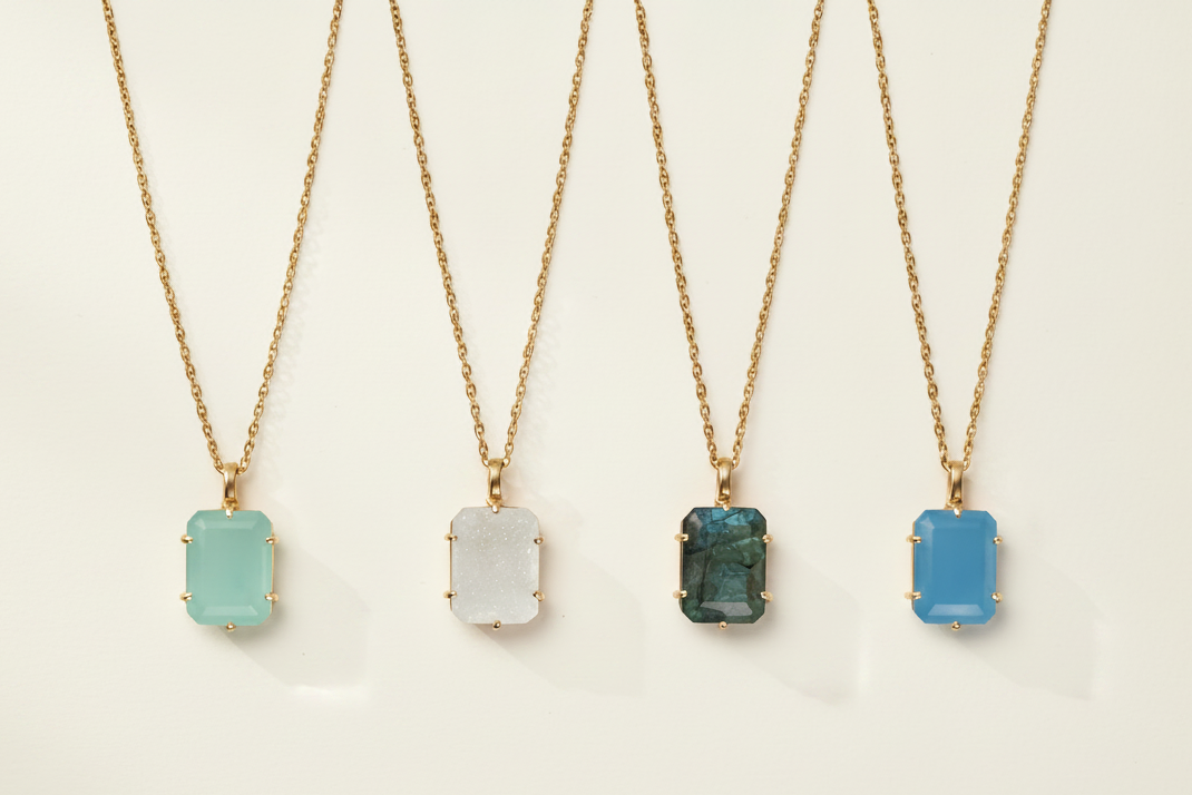 Gold-tone pendant necklace with four emerald-cut stones: aqua, white, dark teal, blue