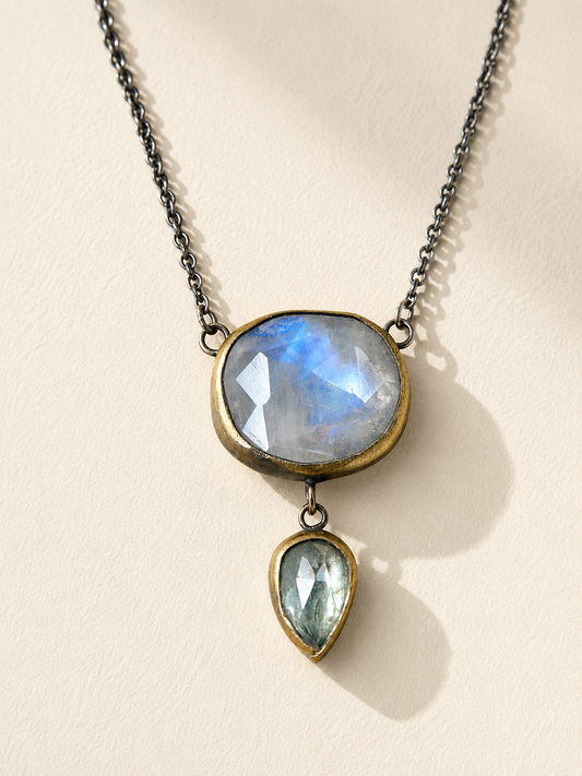 Silver drop necklace with oval blue stone and a gold-rimmed green teardrop charm