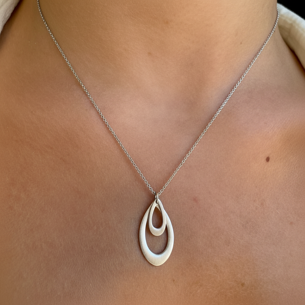 Double leaf teardrop pendant necklace on neckline, silver-tone with gold-tone center