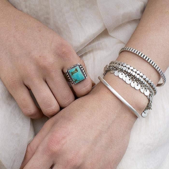 Silver chain bracelet with dangling round disc charms, worn on wrist