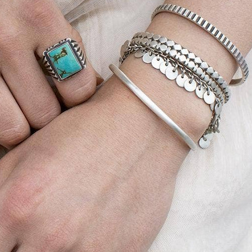 Ridged silver cuff bracelet close-up on wrist, with open ends and textured stripes