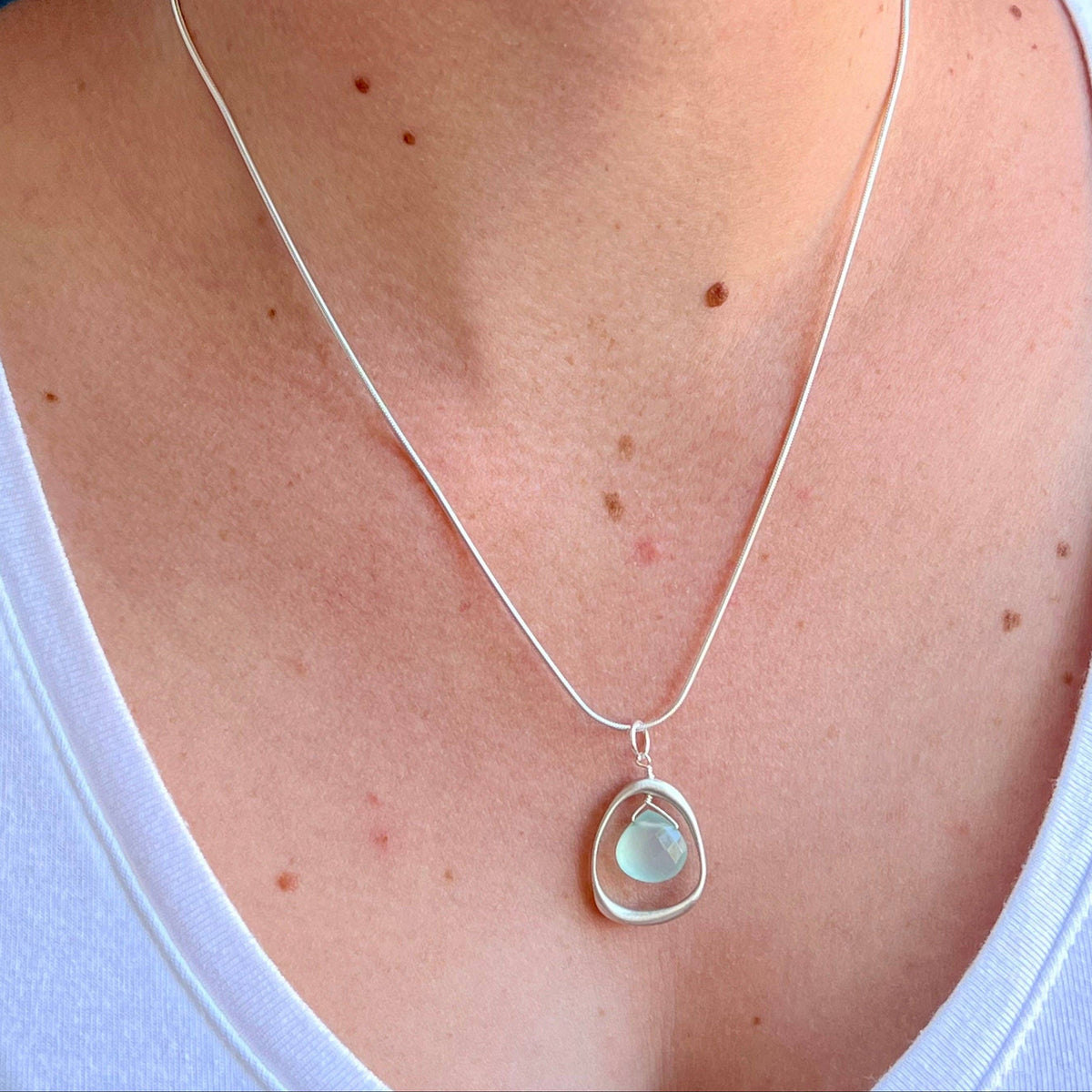 Silver chain necklace with small open-circle bezel and pale green chalcedony pendant
