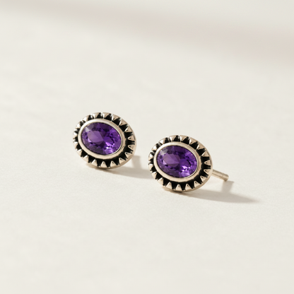 Gemstone stud earrings with purple oval center and silver beaded halo